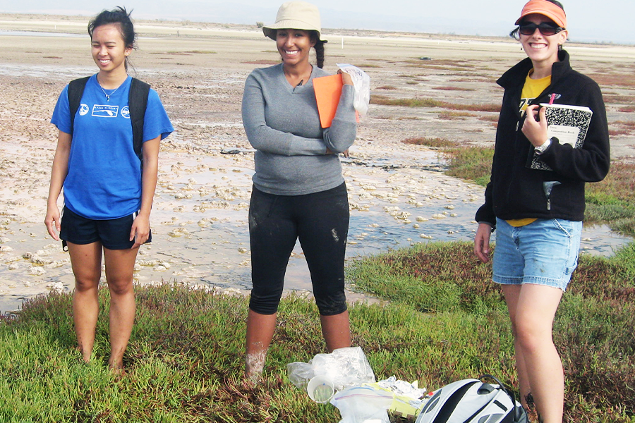 Amanda Tazaz with two colleagues posing for a photo on the edge of the ocean. 