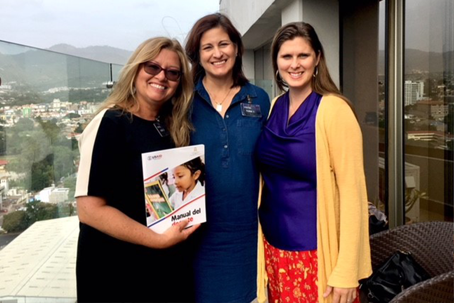 Flavia Ramos-Mattoussi posing with two colleagues holding a book