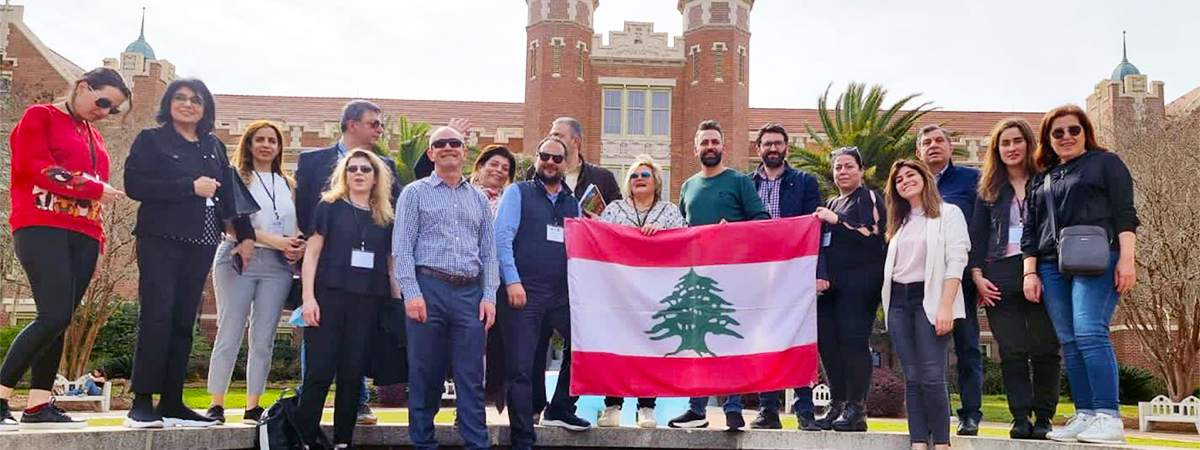 Group photo of participants in the HECD program from Lebanon posing in front of the Westcott building holding a Lebanese flag.