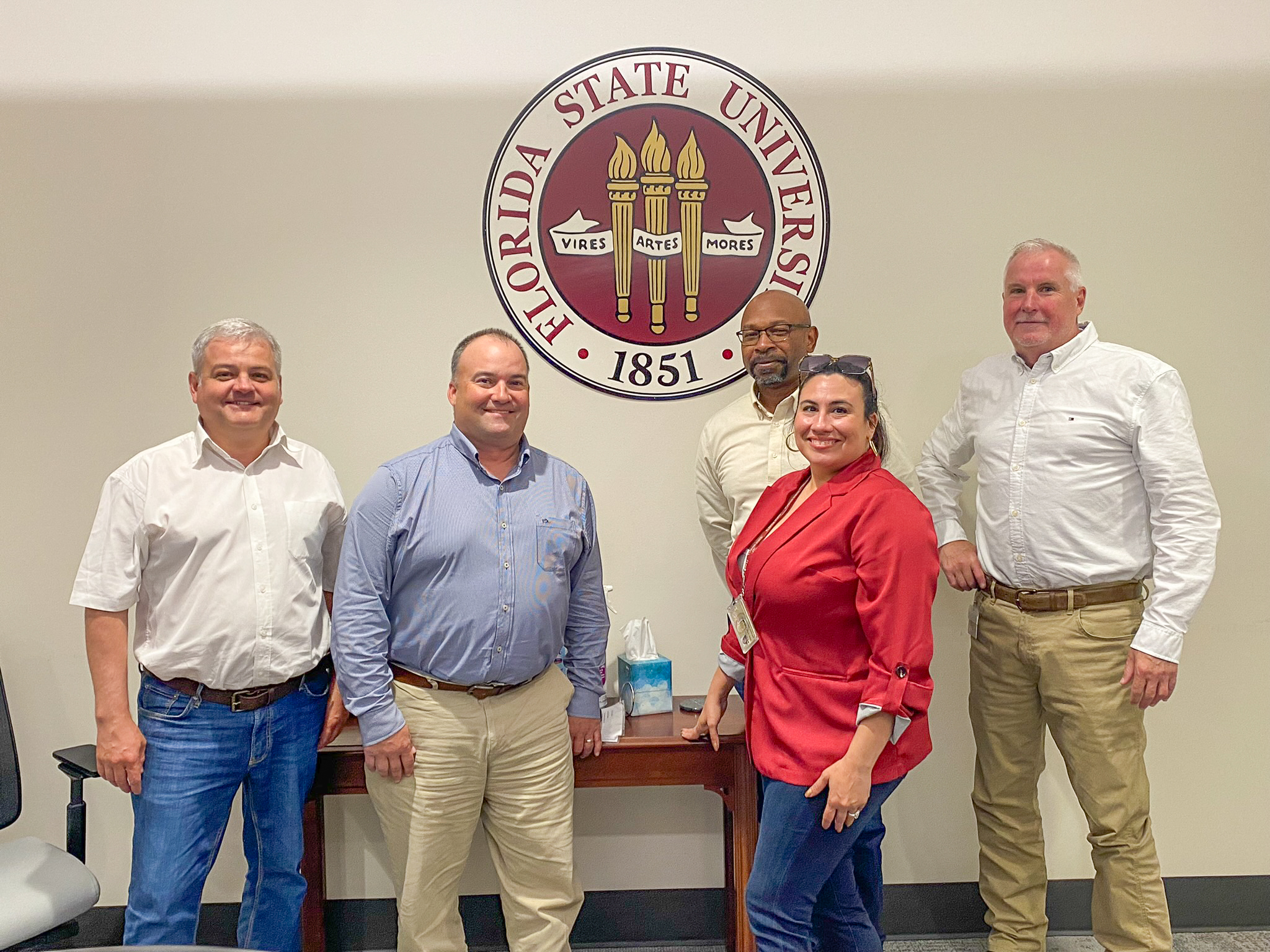 "Dr. Andrii Paziuk poses for a group photo in front of an FSU seal."