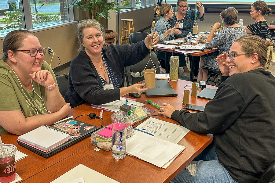 "Three educators at a table working on a project."