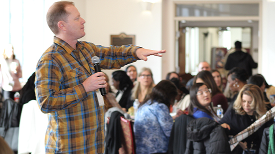 "Dr. Rob Schoen holding a microphone presenting to a crowd at an LSI meeting. "