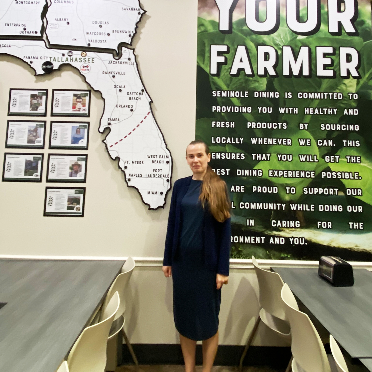 "Dr. Nataliia Safonova posing infront of a large wall graphic with the state of Florida as part of the design."