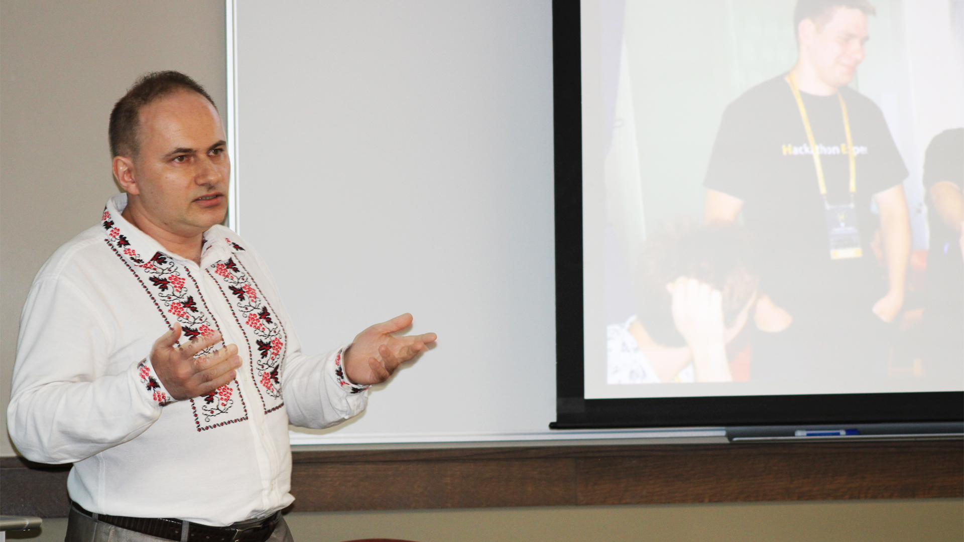 "Dr. Taras Panchenko speaking to a group in front of a projection screen"