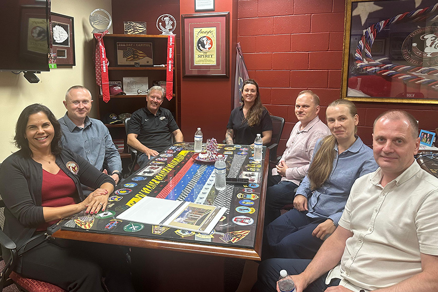 "Ukrainian visitors pose round a table during a meeting at the  FSU student veterans center"