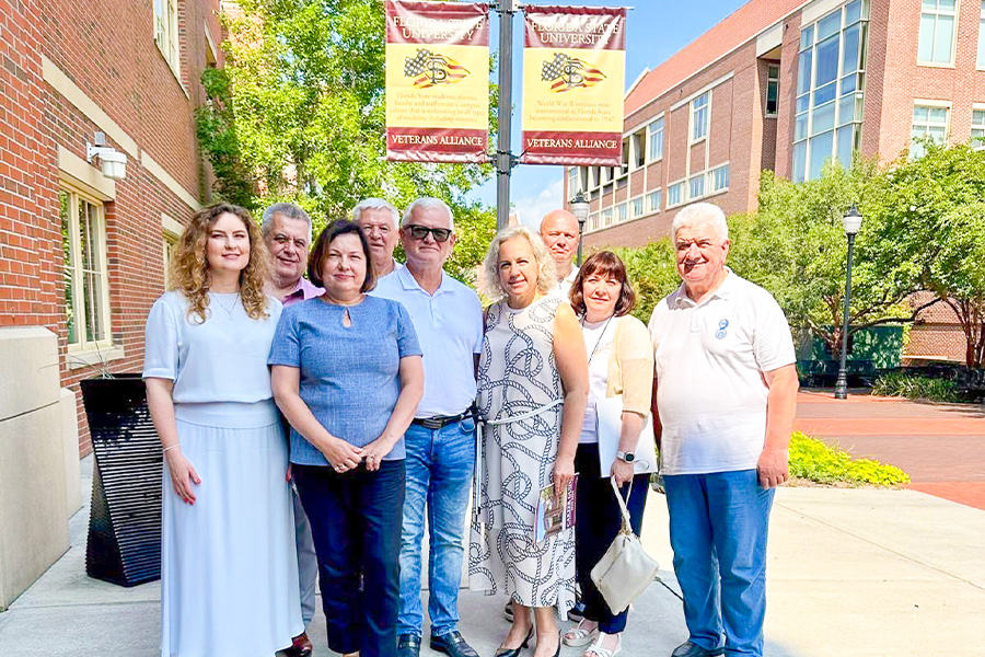 "Ukrainian visitors pose for a photo underneath banners for the FSU student veterans center"