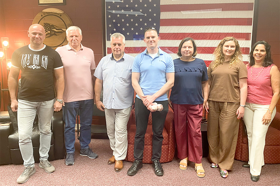 "Ukrainian visitors pose in front of a large USA flag during a meeting at the  FSU student veterans center"