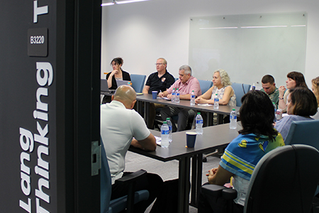 "Carrie Meyers and colleagues sitting around a conference table in discussion"