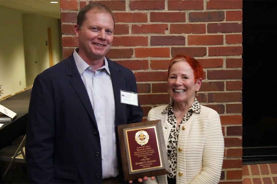 "Dr. Schoen posing with a plaque next to the award presenter."