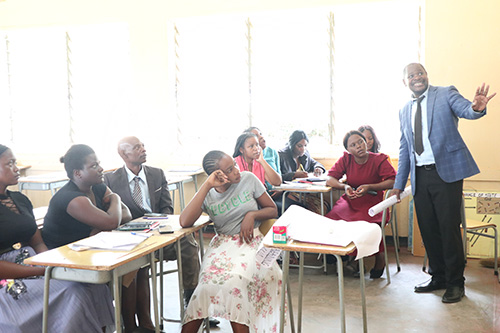 "Man in front of a group of teachers in a classroom in Zambia"
