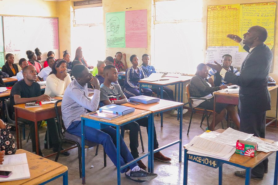 "Man standing at the front of a classroom lecturing a group of teachers in Zambia."