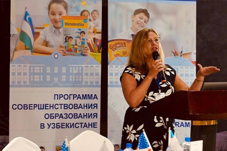 "Dr. Ramos-Mattoussi at a podium with a microphone speaking to a group in Uzbekistan."