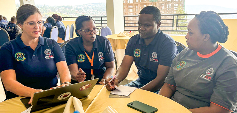 "Small group at a table working around a laptop at the USAID Tunoze Gusoma (Schools and Systems) activity in Rwanda."