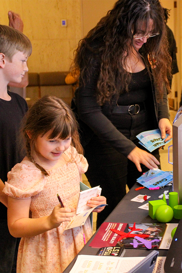 Carrie Meyers at a 3D printer with two children looking on.