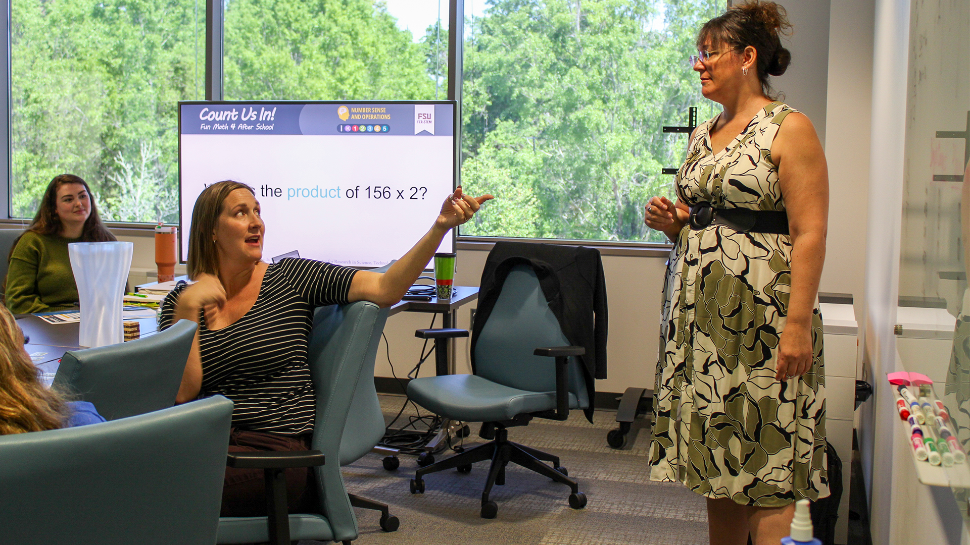 Carrie Meyers at a whiteboard working with a group of afterschool instructors.