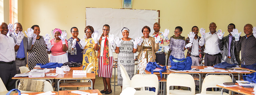 Group photo of educators wearing white gloves, displaying their hands. The gloves have words written all over them.