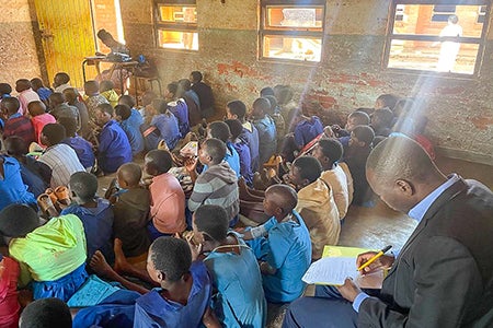 Observer taking notes in the back of a classroom in Malawi.