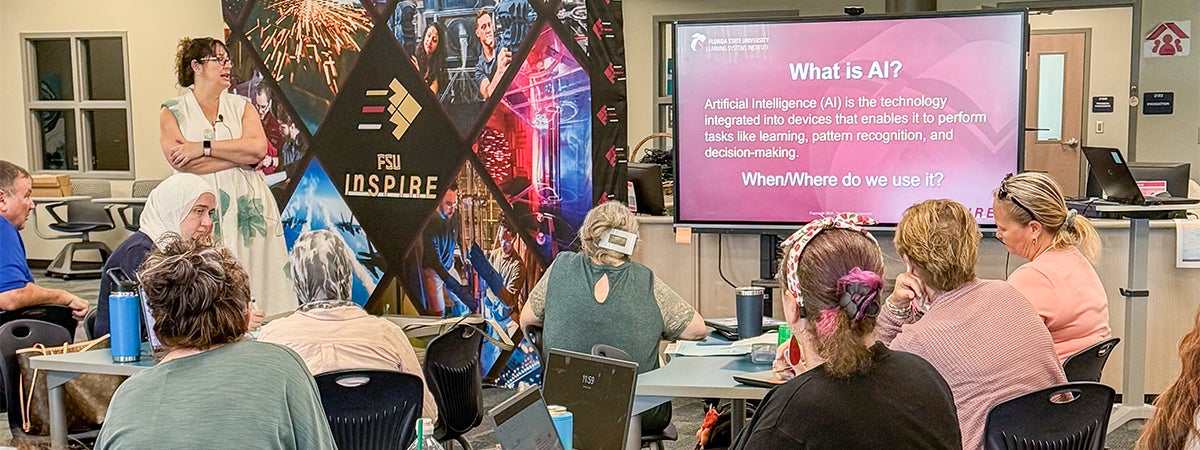 LSI's Carrie Meyers conducting an AI in education session standing next to a flat screen TV.