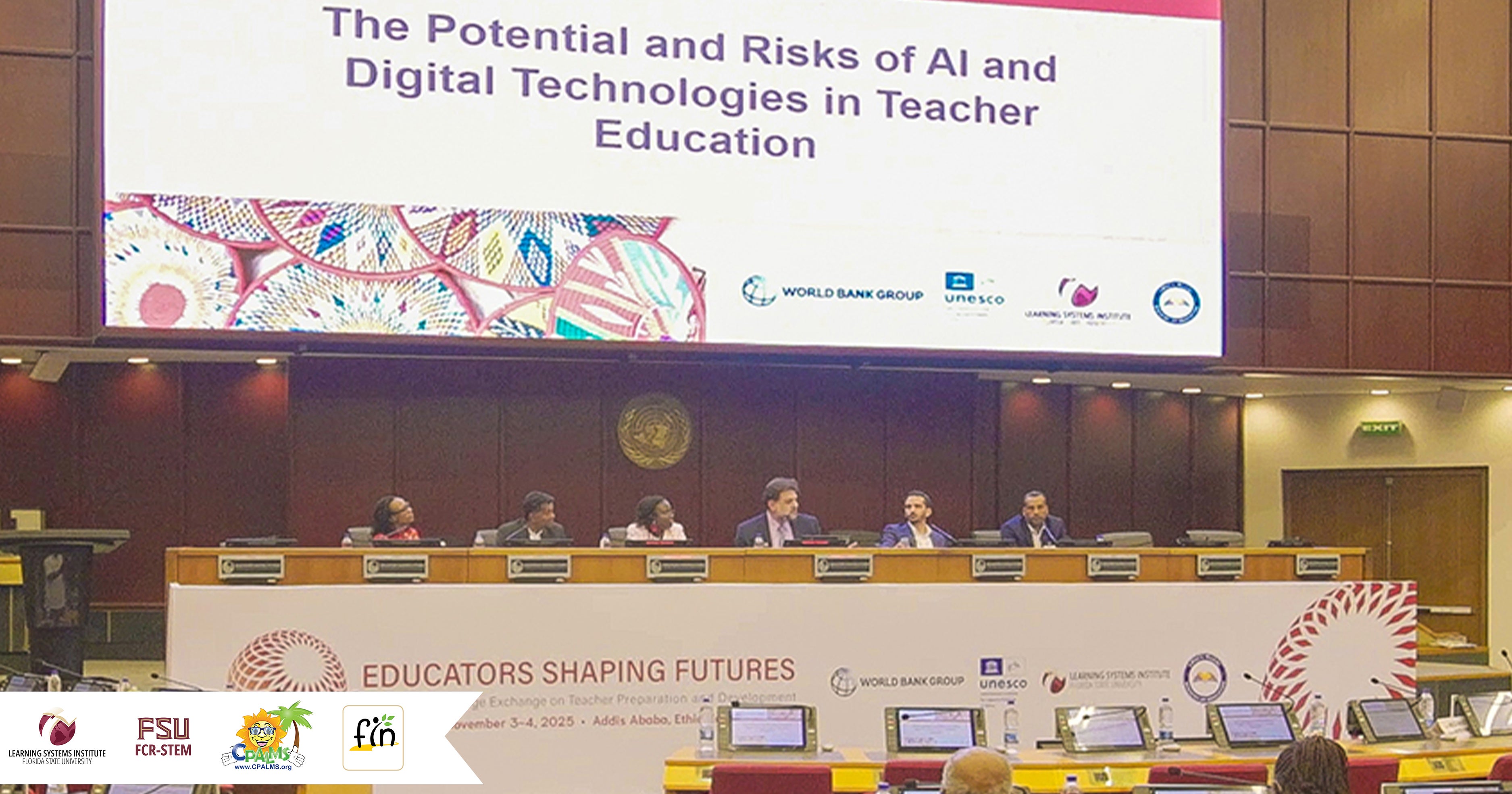 Rabieh Razzouk sitting at a long dias during a panel discussion. There is a massive projection screen behind the group. There are logos for LSI, FCR-STEM, CPALMS and FIN on the right side. 