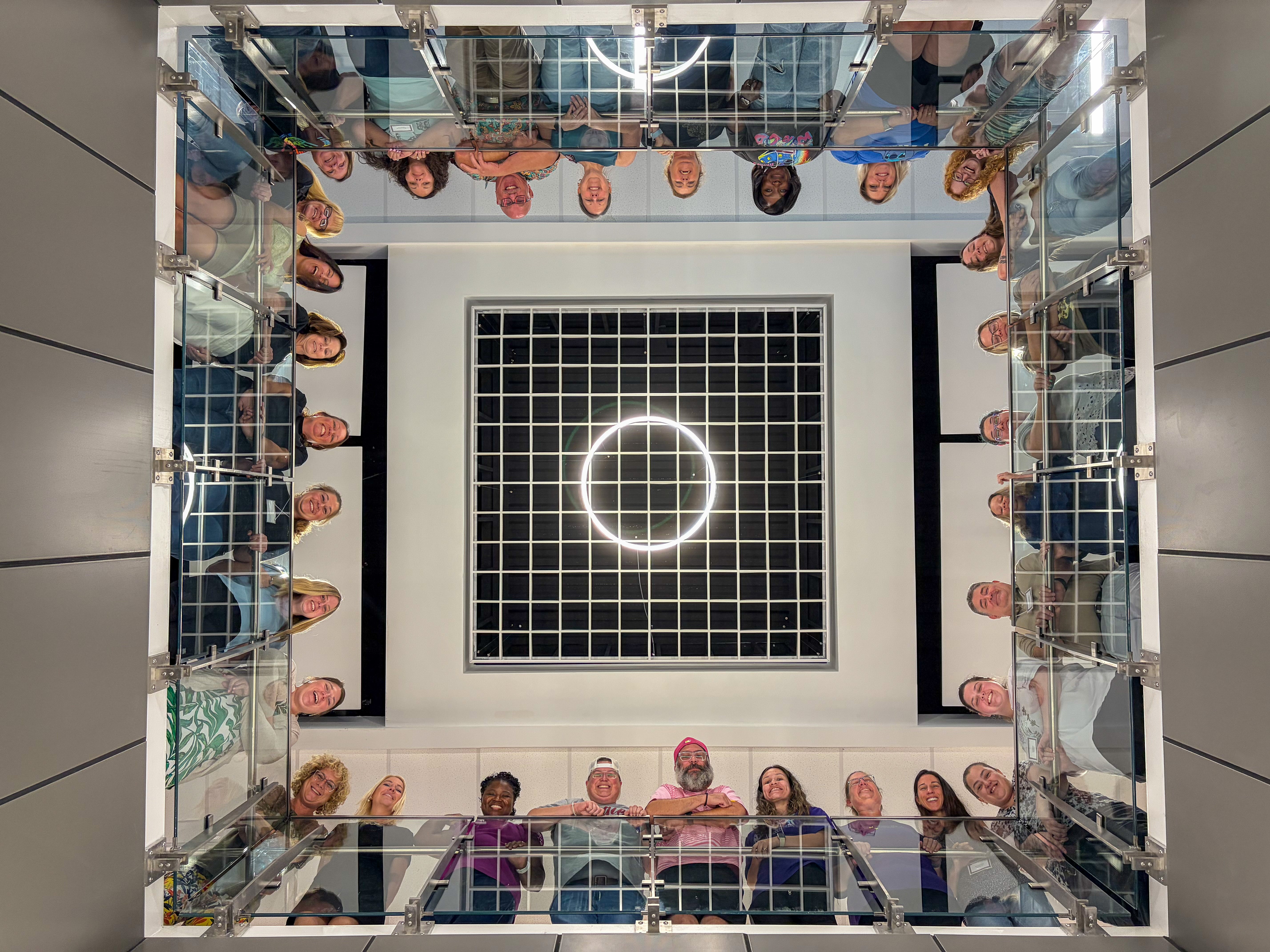 Group photo of educators standing around a large open space elevated. The photo is taken from below.