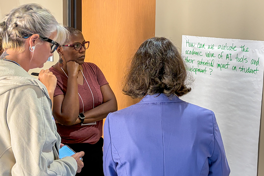 Three individuals stand around a paper on a wall with handwritten text discussing the academic value of AI tools and their impact on student development.