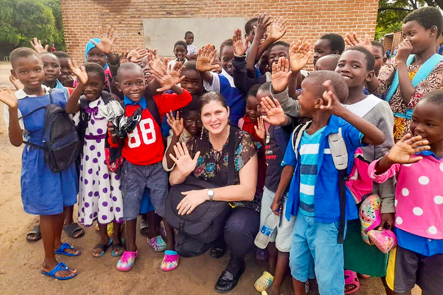 Adrienne Barnes-Story posing with a large group of young children in Africa.