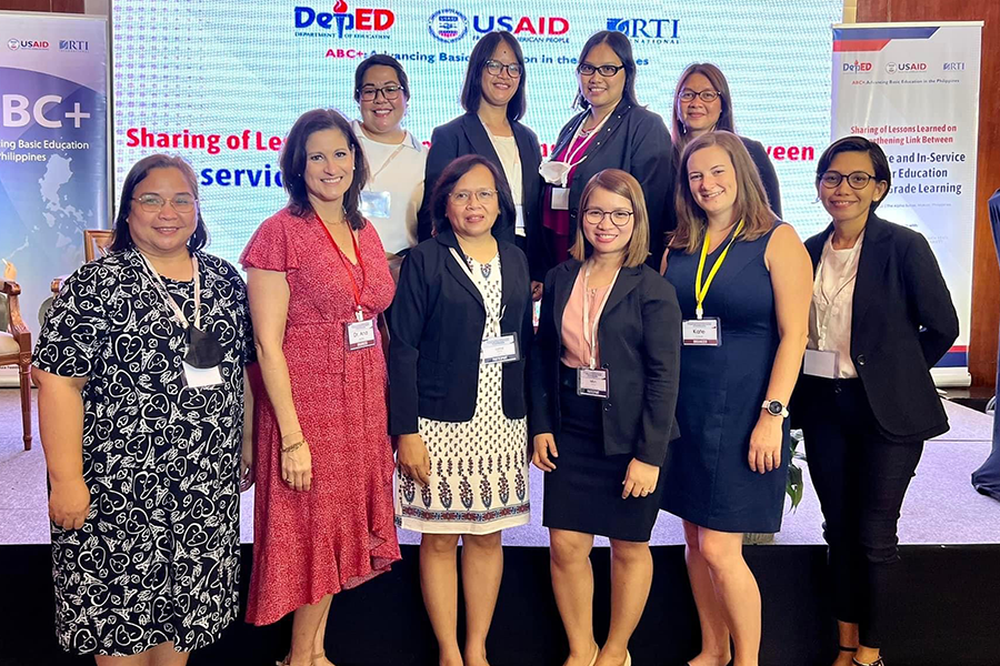 Ana H. Marty posing with a group in the Philippines in front of a large digital screen