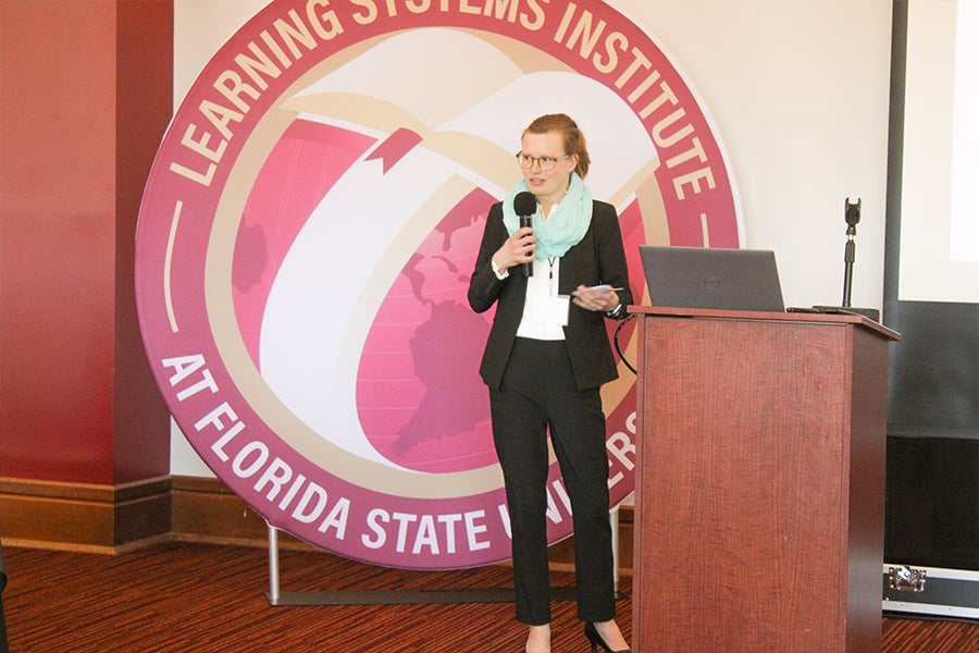 Celia Reddick presenting to a group in front of a large LSI logo banner