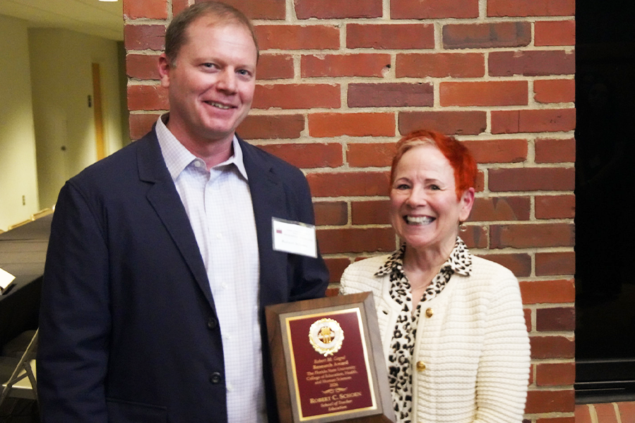 Robert C. Schoen posing with a colleague and a plaque. 