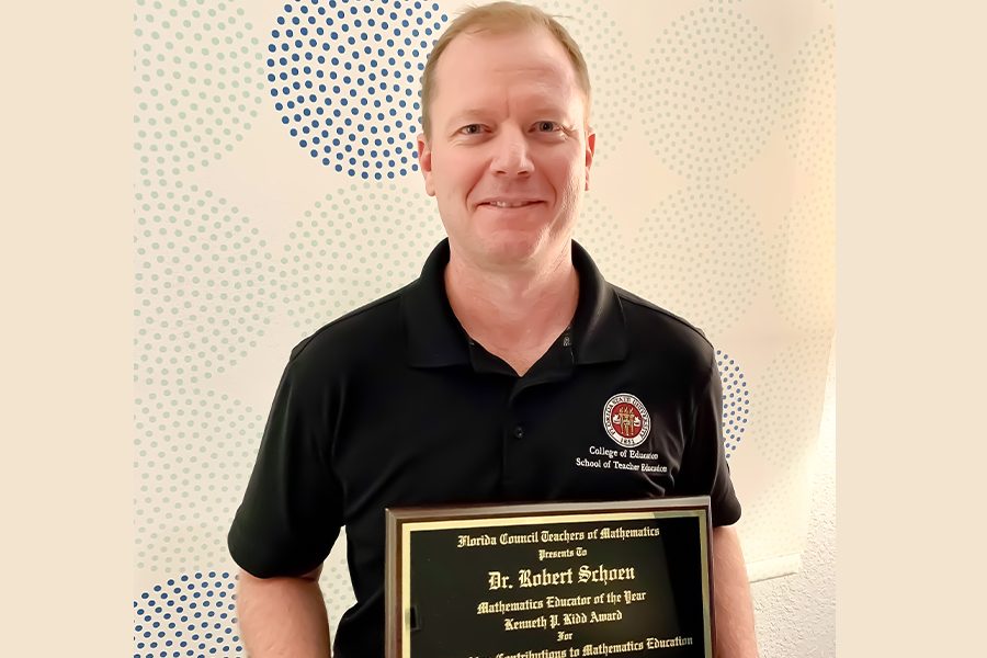 Robert C. Schoen posing with a plaque. 