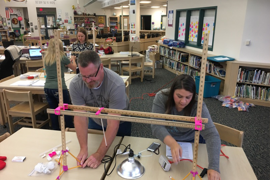 "Two teachers wearing safety goggles working on a STEM project"