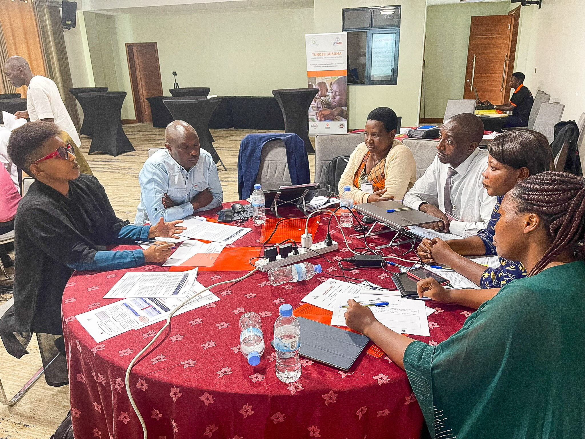 Educators sitting around a table in discussion at a workshop in Rwanda in August of 2024