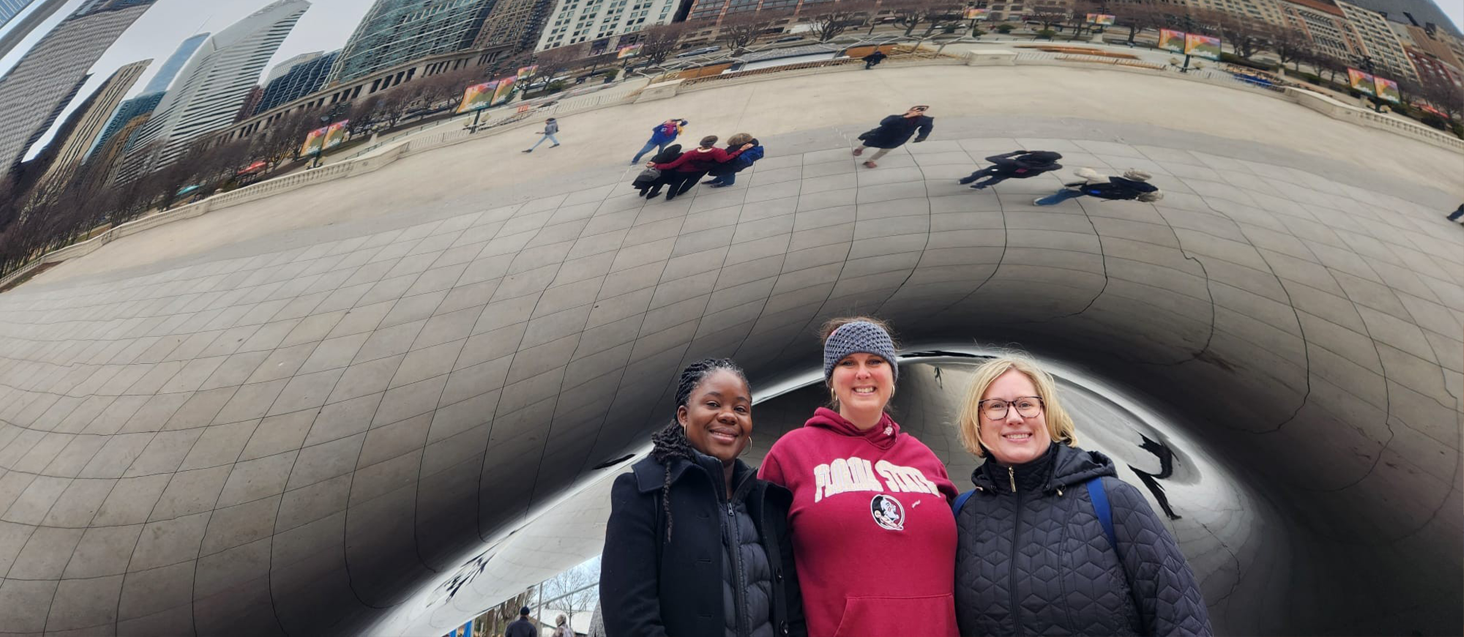 Drs. Brenda Wawire, Adrienne Barnes-Story and Stephanie Zuilkowski posing together in front of the bean in Chicago. 