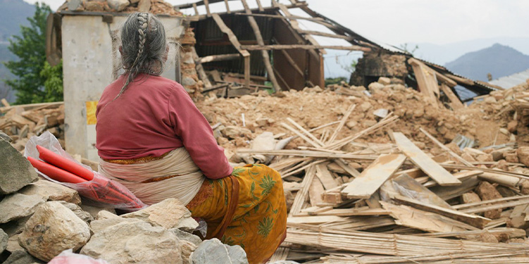 "Woman in Nepal sitting in front of rubble after an earthquake."