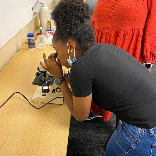 "A girl looking through a microscope"