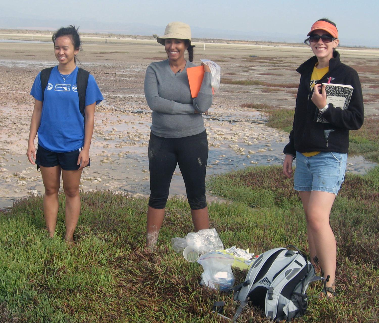 "Dr. Amanda Tazaz and two others standing in the grass near a beach"