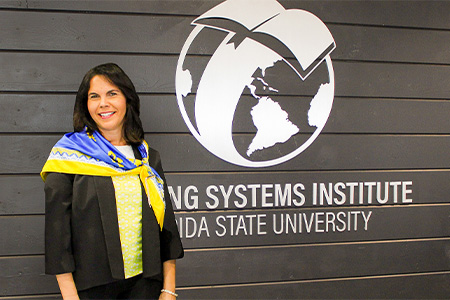 "Dr. Fuentes posing in front of an LSI logo on a wall display"