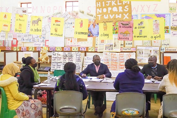A group sitting around a table in a brightly colored classroom during a baseline situational analysis at Teacher Training Colleges in Malawi.