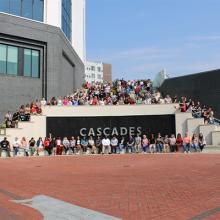 Group photo of 100+ people surrounding a large sign for Cascades Park