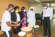 Group standing around a set of drums with two people playing