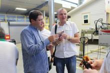 Two participants in CCAP Ukraine in a large warehouse with a home behind them