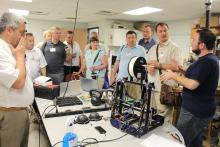 The CCAP Ukraine group standing around a table listening to a presenter