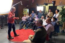 Man standing in front of a large light presenting to a small group