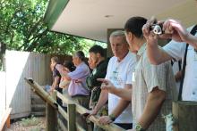 People standing in front of a fence. Some are taking photos. They are at the Santa Fe Teaching Zoo