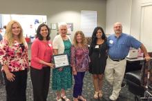 Photo of six people. Dr. Vilma Fuentes is holding a framed certificate