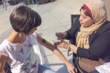 A woman applying body paint to someone's arm