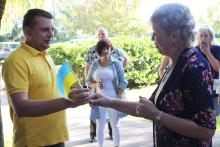 A man is handing a Ukrainian flag to a woman 