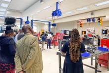 Members of the CCAP South Africa  group inside a classroom at Florida State College in Jacksonville listening to a speaker. There are traffic lights hanging in the background and a car on the rack.