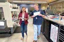 Two people walking together holding papers inside Gulf Coast State College