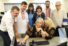 Group of people standing and sitting around a computer